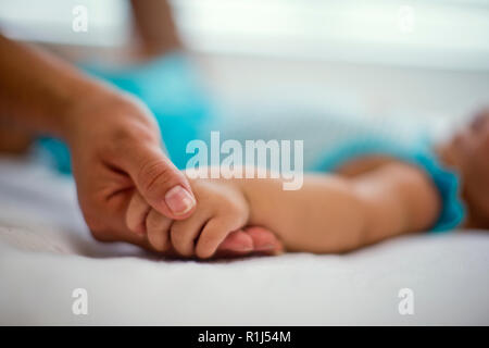 Mother holding her baby daughter's hand. Stock Photo