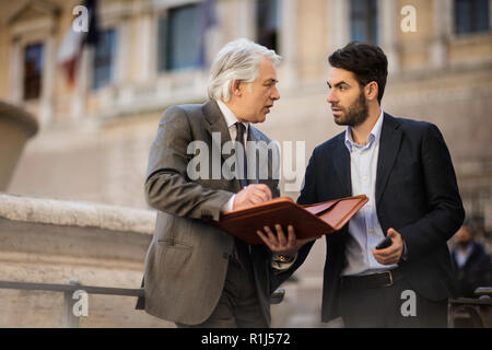 Mature businessman has a chance meeting with a young colleague while they are out in the city. Stock Photo