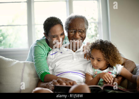 Grandparents reading with young granddaughter. Stock Photo