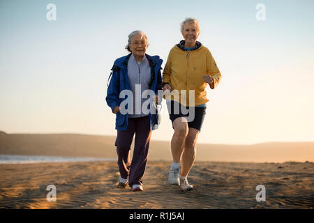 Two senior woman exercising together on the beach. Stock Photo