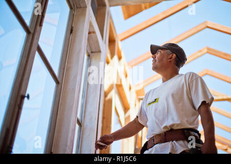 Middle aged builder working on the wooden framing of a building. Stock Photo