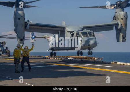 ATLANTIC OCEAN (Oct. 4, 2018) Sailors assigned to the Wasp-class amphibious assault ship USS Iwo Jima (LHD 7) signal an MV-22B Osprey, attached to Marine Medium Tiltrotor (VMM) 365 (Reinforced), on the ship’s flight deck October 4, 2018. Iwo Jima recently departed its homeport of Naval Station Mayport following the completion of a scheduled continuous maintenance availability. Stock Photo