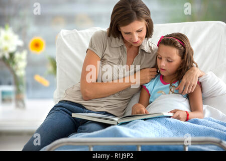 Mother reading young daughter a story in hospital. Stock Photo