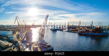 Aerial; drone view of port with shipyard silhouettes on the horizon; industrial cityscape in sunny weather with blue sky; process of ship repairing, l Stock Photo