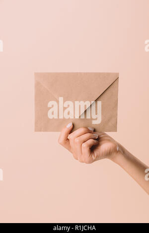 cropped shot of woman holding envelope isolated on beige Stock Photo