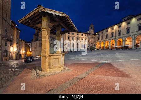 Arezzo, Italy. Old well located on Piazza Grande square at dusk Stock Photo