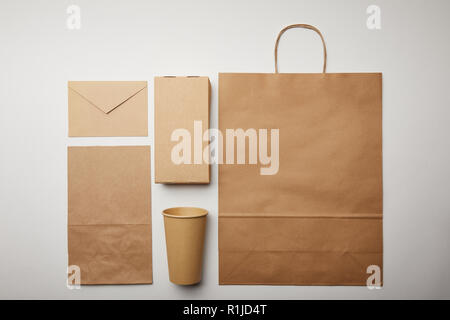 flay lay with envelope, paper cup, food delivery paper bag on white surface, minimalistic concept Stock Photo