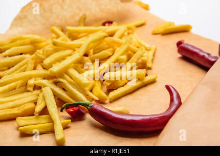 tasty french fries with spicy peppers on parchment paper on white Stock Photo