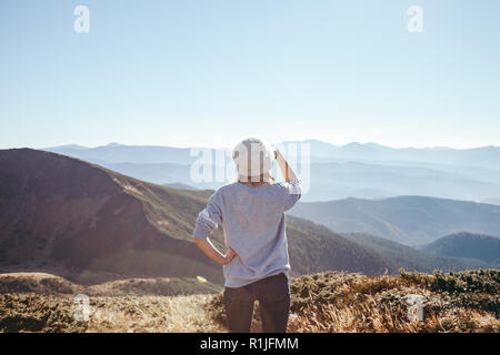 rear view of female explorer looking at scenic mountains on sunny day, Carpathians, Ukraine Stock Photo