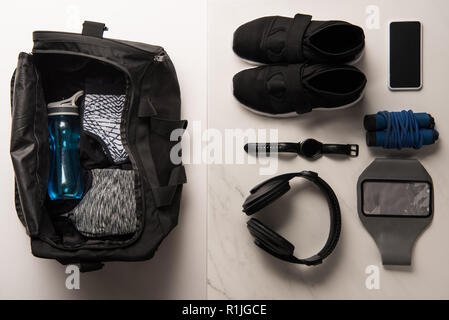 flat lay with sports bag and arranged sports equipment on white and marble Stock Photo
