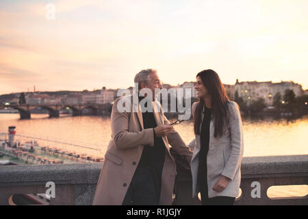 Excited man and woman business partners standing by a river in city at dusk. Stock Photo