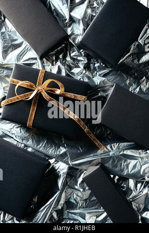 flat lay with arranged gift with golden ribbon and blank black boxes on silver wrapping paper background Stock Photo