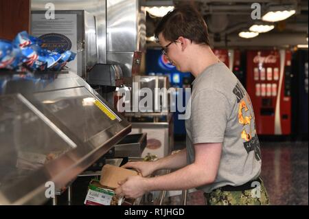 NORWEGIAN SEA (Oct. 20, 2018) Operations Specialist Joseph Lester stocks a snack bar on the aft mess decks aboard the Nimitz-class aircraft carrier USS Harry S. Truman (CVN 75). Currently operating in the U.S. Sixth Fleet area of operations, Harry S. Truman will continue to foster cooperation with regional allies and partners, strengthen regional stability, and remain vigilant, agile and dynamic. Stock Photo