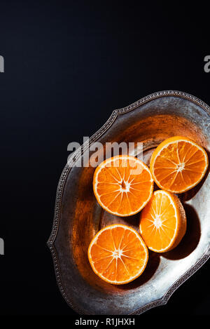 top view of mandarins and metal bowl on black backdrop Stock Photo