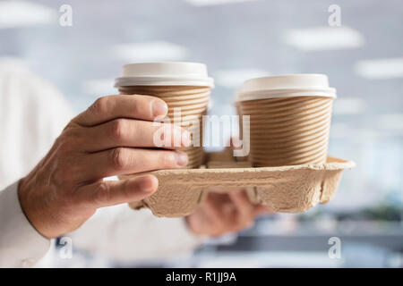 Businessman carrying coffee take out disposable cups for office meeting Stock Photo