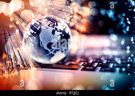 Fibre optics around blue planet on laptop computer keyboard Stock Photo
