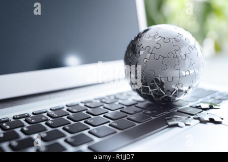 Global strategy solution concept - chrome earth jigsaw puzzle on laptop keyboard Stock Photo