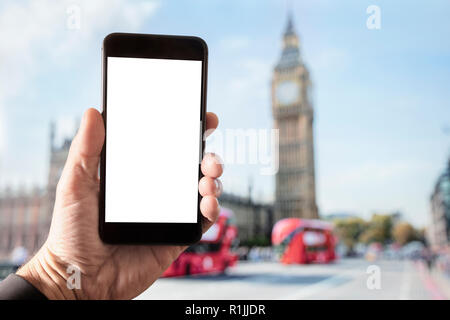 Hand holding smartphone with blank screen in London in front of Big Ben and Houses of Parliament on Westminster Bridge Stock Photo