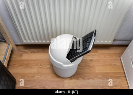 Computer Keyboard in Trash Can on Office Floor, looking down Stock Photo