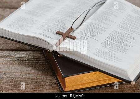 close-up shot of holy bibles with cross on wooden table Stock Photo