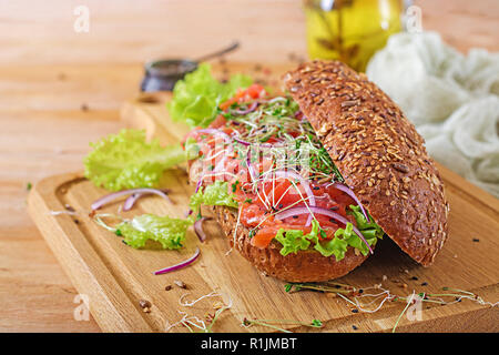 Salmon sandwich - smorrebrod with cheese cream and microgreen on wooden table. Stock Photo