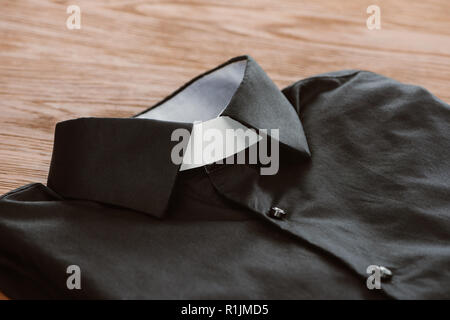 close-up shot of clerical shirt with white collar on wooden surface Stock Photo