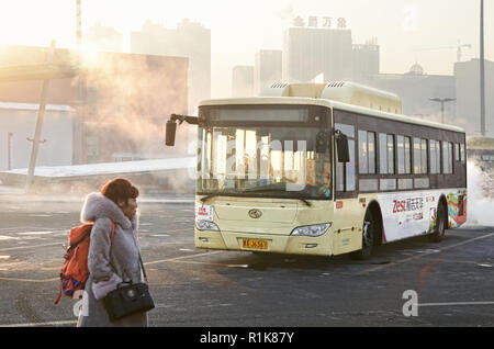 Woman passenger and public bus in parking area of Harbin West Railway Station Stock Photo