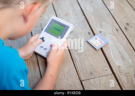 Young boy using his nintendo gameboy to play computer games. Nineties setting. indoors setting. Stock Photo