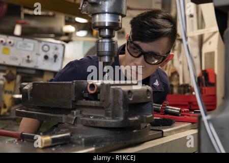 ATLANTIC OCEAN (Oct. 14, 2018)  Machinery Repairman 3rd Class Jerome Pascual operates a milling machine while repairing a component of the bridge train aboard the Wasp-class amphibious assault ship USS Kearsarge (LHD 3). Kearsarge is underway for amphibious ready group training and deployment certifications. Stock Photo