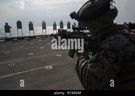 Lance Cpl. Isaiah J. Cotton, a rifleman with Company F, Battalion Landing Team, 2nd Battalion, 5th Marines, fires an M4 carbine during marksmanship training aboard the amphibious assault ship USS Wasp (LHD 1), underway in the East China Sea, Oct. 16, 2018. Cotton, a native of Springfield, Illinois, graduated Springfield Southeast  High School in May 2015; he enlisted November 2016. Company F, the helicopter-borne raid element with BLT 2/5, conducted this training to refine marksmanship skills during the fall patrol. The 31st Marine Expeditionary Unit, the Marine Corps’ only continuously forwar Stock Photo