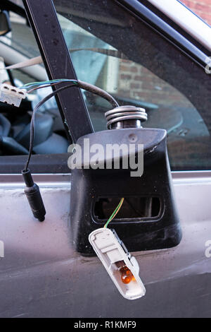 Broken drivers wing mirror hanging off a written off crash damaged citroen c4 car on a recovery trailer Stock Photo