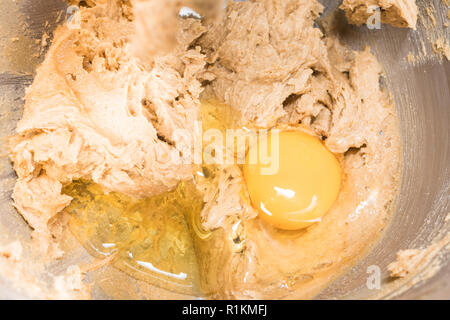cake making - adding egg to creamed brown sugar and butter - cake mixture Stock Photo