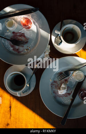 Top view dirty dishes after cake and coffee for two. Candid photo table cafe with leftovers of lunch, crumpled napkins, forks, knives and cups in the  Stock Photo