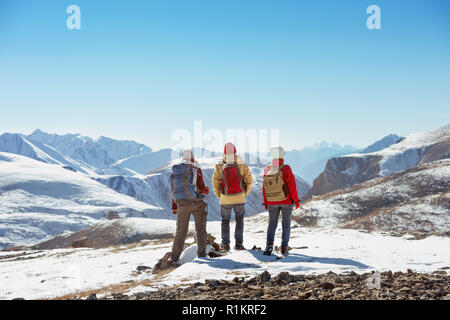 Three tourists stands on the top of mountain pass and looks at view Stock Photo