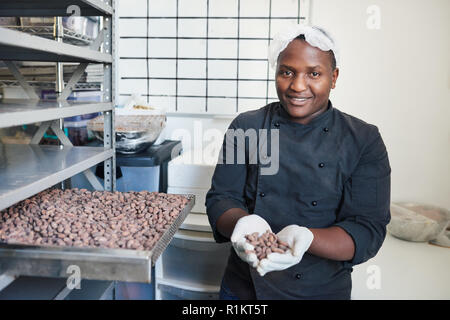 Smiling worker selecting cocoa beans from a factory tray Stock Photo