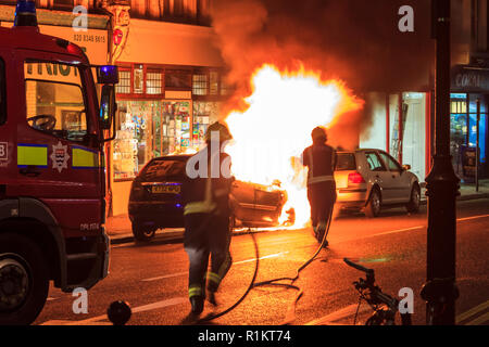 London Fire Brigade officers tackle a vehicle fire in Crouch End, North London, UK, November 2012 Stock Photo