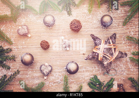 Christmas fir green frames an old real wooden background. Christmas balls in brown and natural wood elements create a Christmas atmosphere. Stock Photo