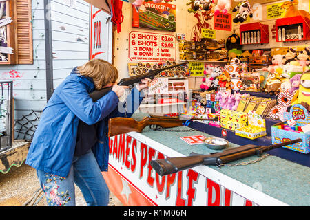 Teenager firing an air rifle at a fairground shooting gallery, London, UK Stock Photo