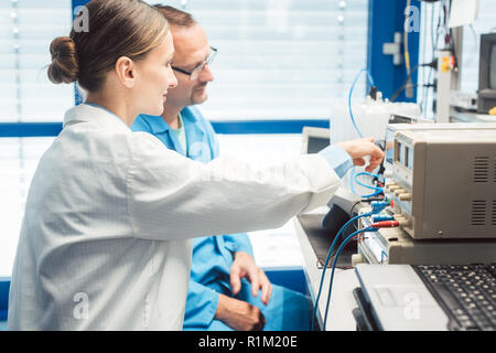 Team of electronic engineers testing a product prototype on test bench in the lab Stock Photo