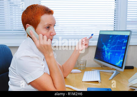 Beautiful girl stock broker talking on the phone in the office Stock Photo