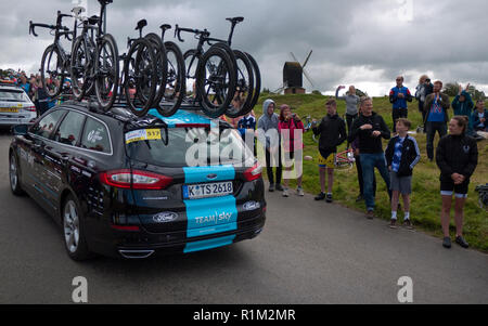 Team Sky car passes supporters and windmill at 2017 Tour Of Britain cycle race, Brill, Buckinghamshire, England Stock Photo