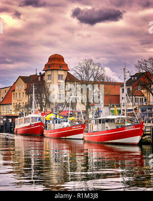 Three fishing boats in Warnemünde at the old canal or old creek. The once sleepy fishing village was founded in 1200. Stock Photo