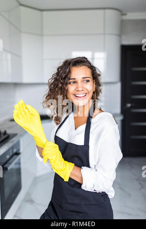Portrait of young attractive caucasian brunette housewife at kitchen wearing the yellow rubber gloves. Stock Photo