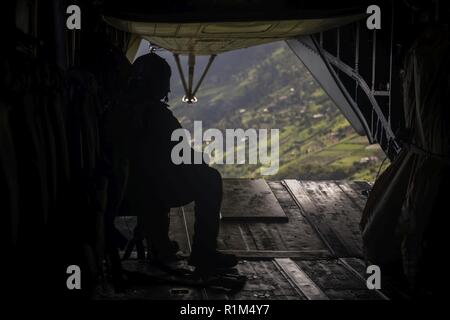 U.S. Marine Corps Staff Sgt. David Linkenhoker, a CH-53E Super Stallion crew chief with Marine Heavy Helicopter Squadron (HMH) 463, looks out the back of a CH-53E while flying from Marine Corps Base Hawaii to Schofield Barracks as part of Operation Steel Crucible, Oct. 17, 2018. HMH-463 teamed up with U.S. Soldiers assigned to 3rd Regiment, 7th Field Artillery Battalion, to conduct a Helicopter Support Team exercise, transferring a M777 towed 155mm howitzer from one landing zone to another. Stock Photo