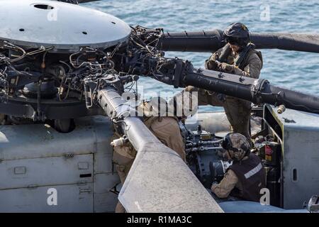 ARABIAN SEA (Oct. 21, 2018) Marines assigned to the “Sea Elks” of Marine Medium Tiltrotor Squadron (VMM) 166 (Reinforced) conduct preflight checks on a CH-53E Super Stallion helicopter on the flight deck of Wasp-class amphibious assault ship USS Essex (LHD 2) during a regularly scheduled deployment of Essex Amphibious Ready Group and 13th Marine Expeditionary Unit. USS Essex is a flexible, and persistent Navy-Marine Corps team deployed to the U.S. 5th Fleet area of operation in support of naval operations to ensure maritime stability and security in the Central Region, connecting the Mediterra Stock Photo