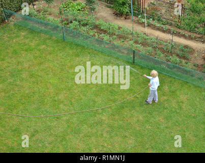 Woman watering a garden lawn shot from above - bird's-eye view Stock Photo
