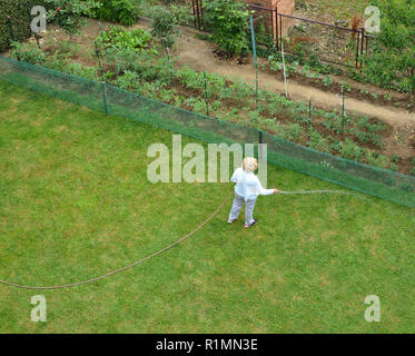 Woman watering a garden lawn shot from above - bird's-eye view Stock Photo