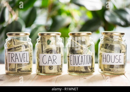 close-up view of glass jars with dollar banknotes and inscriptions travel, car, education, house Stock Photo