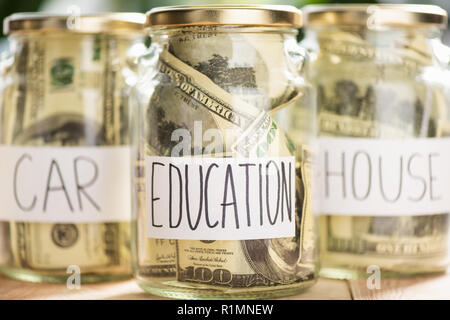 close-up view of glass jars with dollar banknotes and inscriptions car, education, house Stock Photo