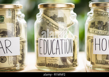 glass jars with dollar banknotes and inscriptions car, education, house Stock Photo